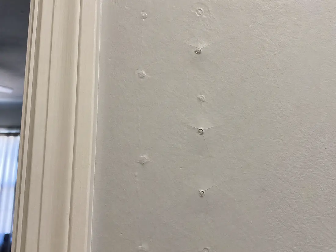 Nail pops pushing through drywall compound in a line